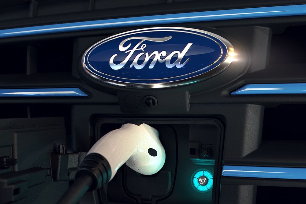 Zbliżenie na biały kabel ładujący podłączony do przedniego portu ładowania samochodu elektrycznego Ford.