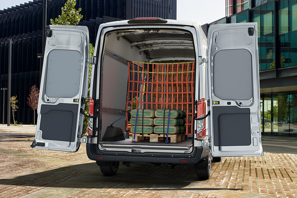 Widok z tyłu wnętrza białego vana Forda zaparkowanego w pobliżu budynków biurowych.