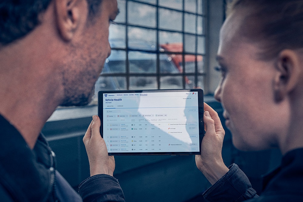 Menedżerowie floty przeglądający telematykę pojazdów na tablecie.