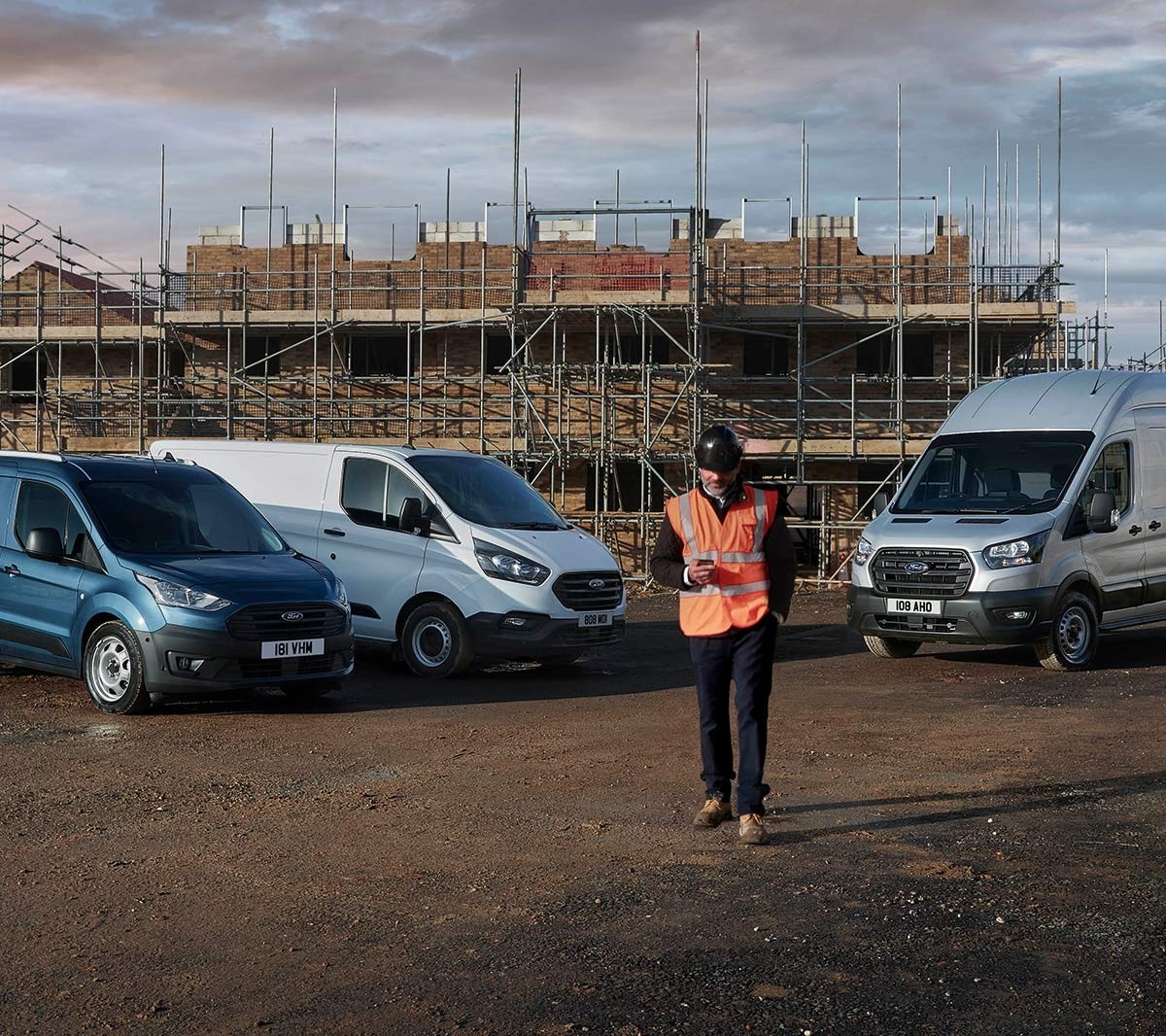Building site with man in high viz jacket and various Ford cars