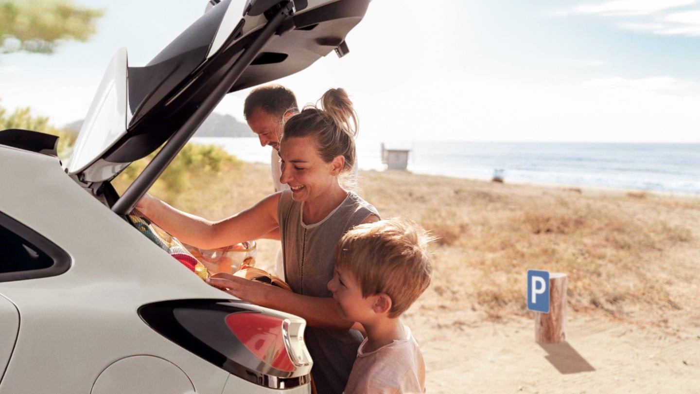 Rodzina na plaży, pakująca przedmioty do bagażnika samochodu marki Ford.