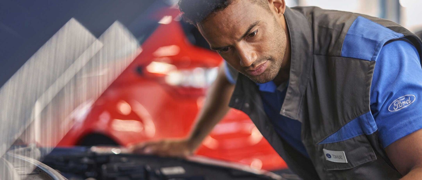 Service employee and customer standing under the car at workshop