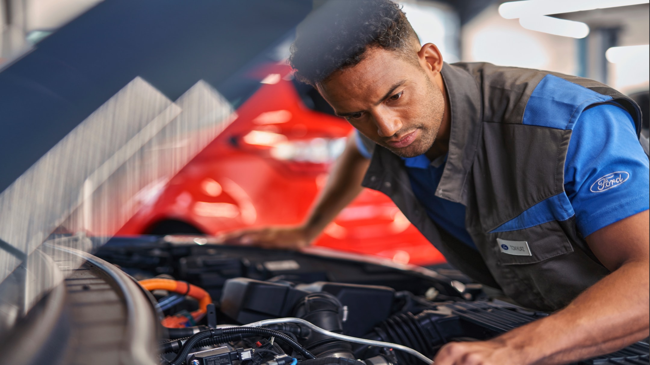 Doświadczony mechanik Forda pracuje nad silnikiem samochodu podczas realizacji Kontraktu Serwisowego Ford Używane.