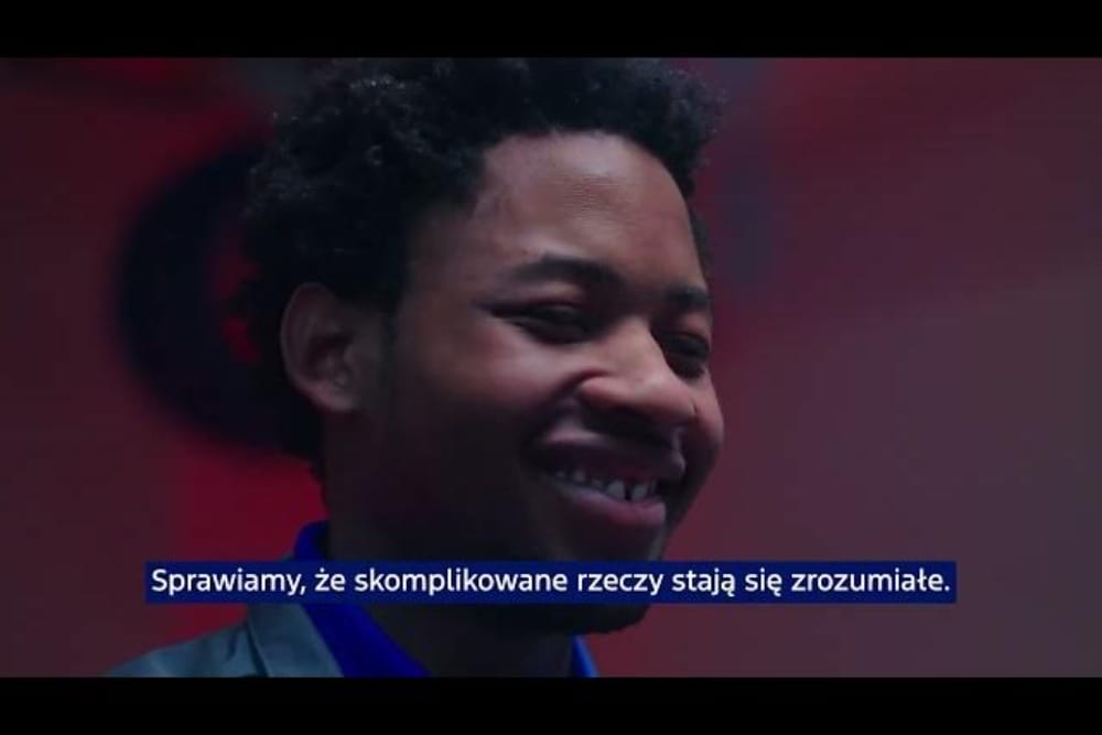 Uśmiechnięta osoba w zbliżeniu na tle w ciepłych, czerwonych barwach.